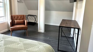 Une pièce avec un canapé en cuir marron, un tapis blanc à motifs, une petite table en bois et un téléviseur fixé au mur.