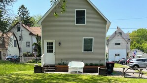 Un jardin avec un foyer, une chaise blanche et un banc.