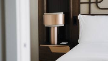A modern hotel room with a bed, a nightstand, and a lamp.