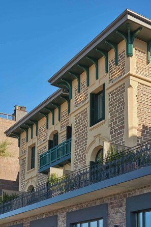 A multi-story building with a brick facade, green window frames, and a balcony with a metal railing. - Nobu Hotel San Sebastián (San Sebastián)