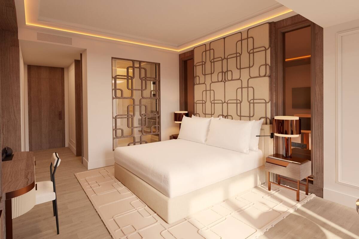 A modern bedroom with a large bed, bedside tables, a desk, and a chair.