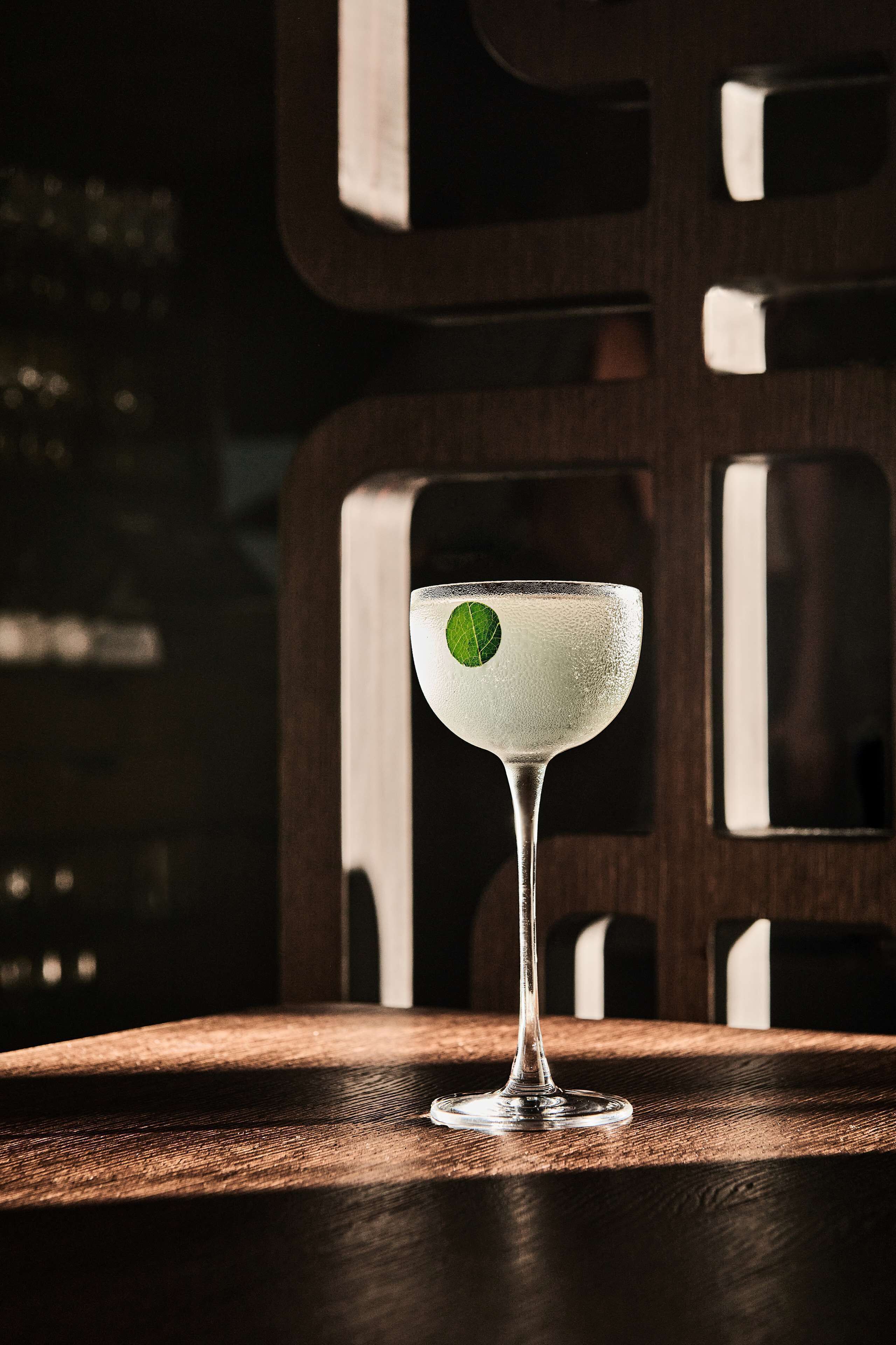 Una copa de martini con un adorno de lima sobre una mesa de madera.
