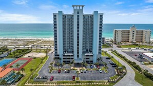 Ein Hochhaus-Hotel mit mehreren Balkonen, einem Parkplatz und Blick auf den Strand.