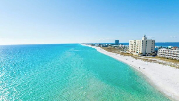 Ein Küstenhotel mit Blick auf den Strand, klares türkisfarbenes Wasser und eine weiße Sandküste.