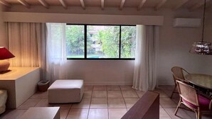 A room with a large window, a bench, a table, and a chair. - CACAO SUITE IN CORONADO LUXURY  CLUB & SUITES - Kitchen & golf course A (Playa Coronado)