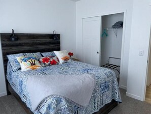Ein Schlafzimmer mit einem Bett, einem Holz-Kopfteil, einem Kleiderschrank und einer Tür.