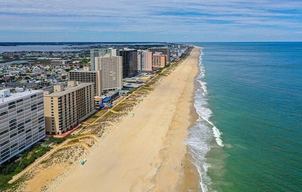 Un paysage urbain côtier avec une longue plage de sable, des immeubles de grande hauteur et une vue sur l’océan.