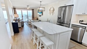 A modern kitchen with a large island, stainless steel appliances, and a view to the outside.
