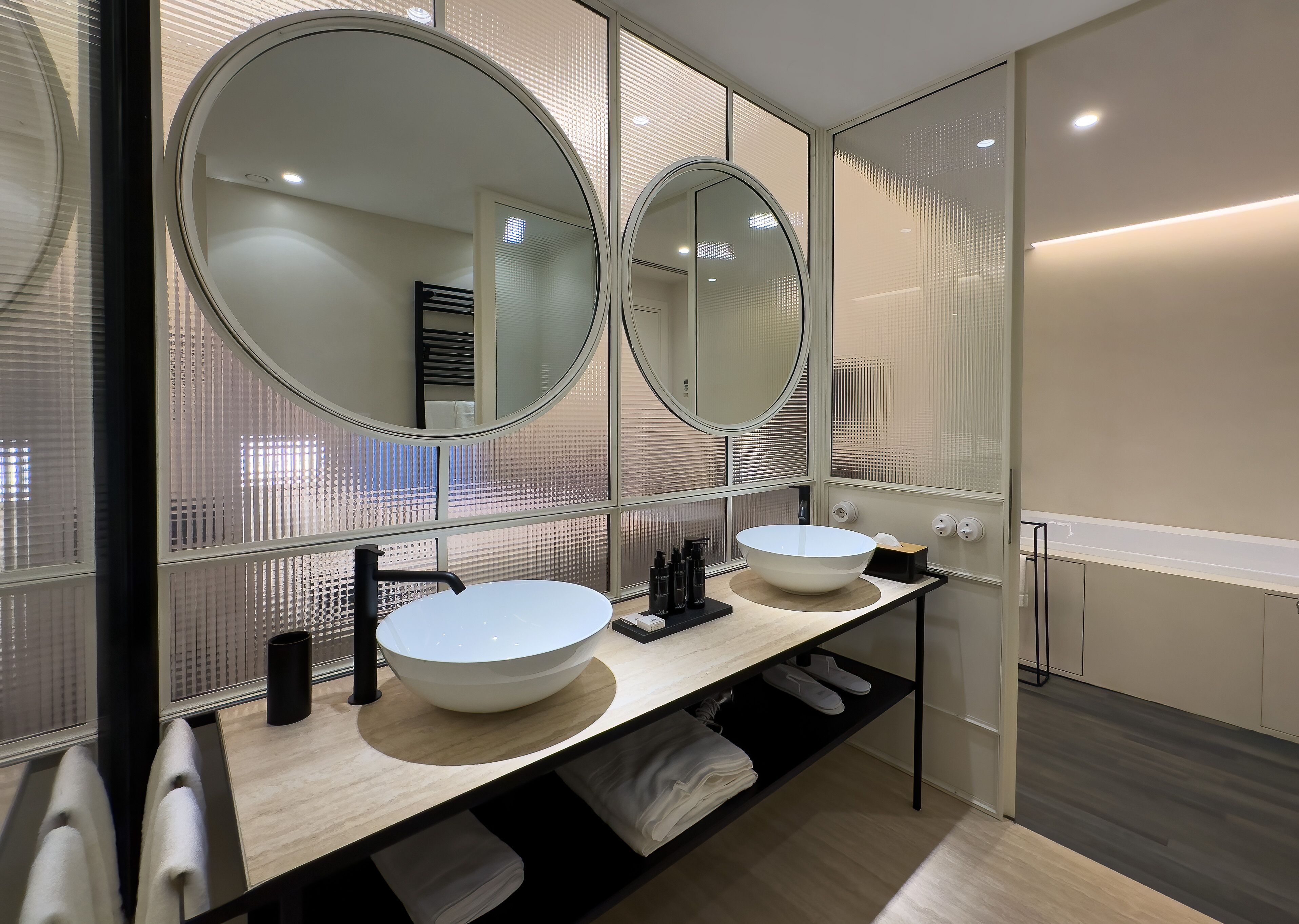 A modern bathroom with two sinks, a large mirror, and a towel rack.