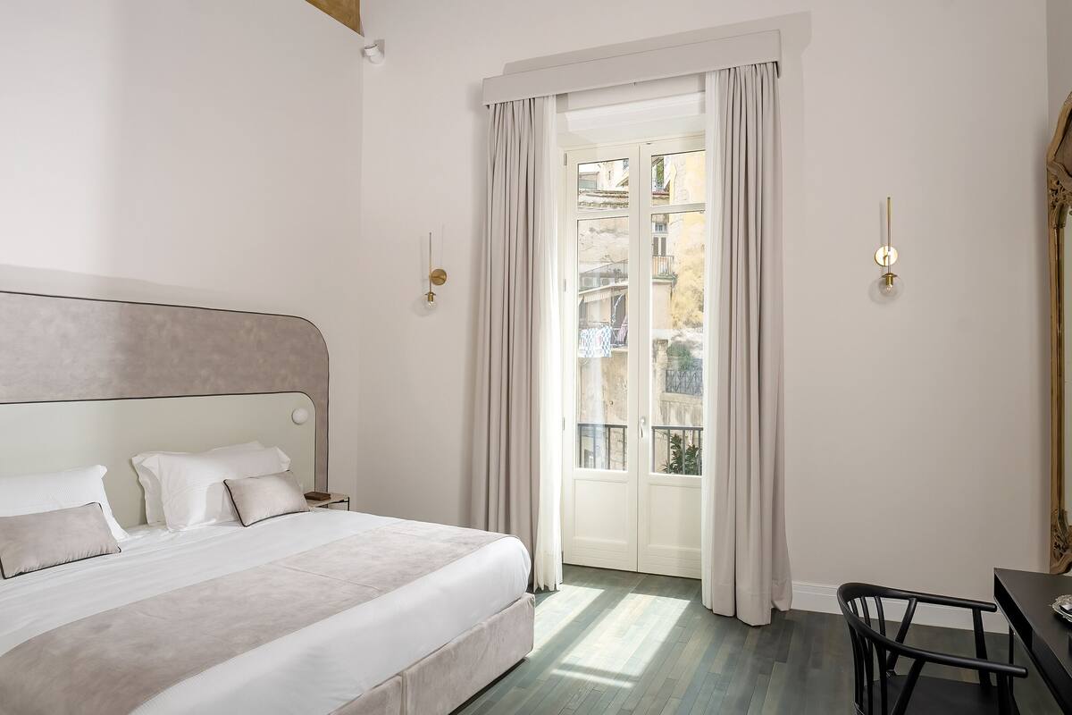 A bedroom with a large bed, a wooden ceiling, and a view through a door.