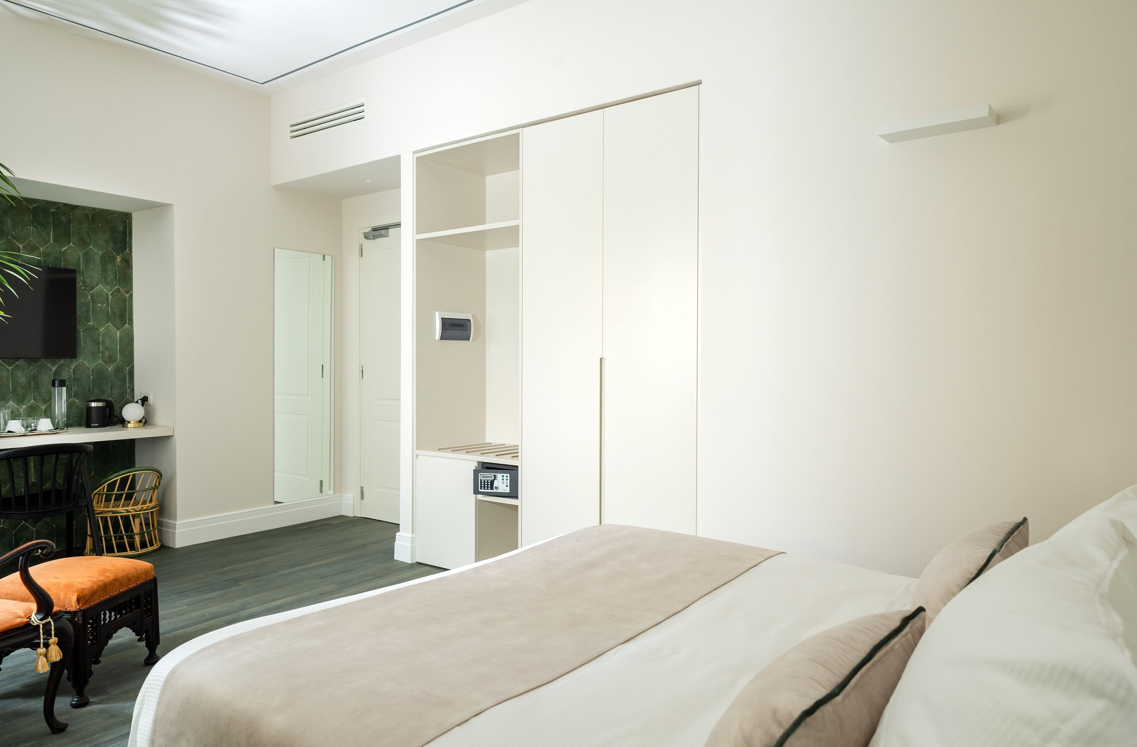 A bedroom with a bed, a desk, a chair, a wardrobe, and a television.