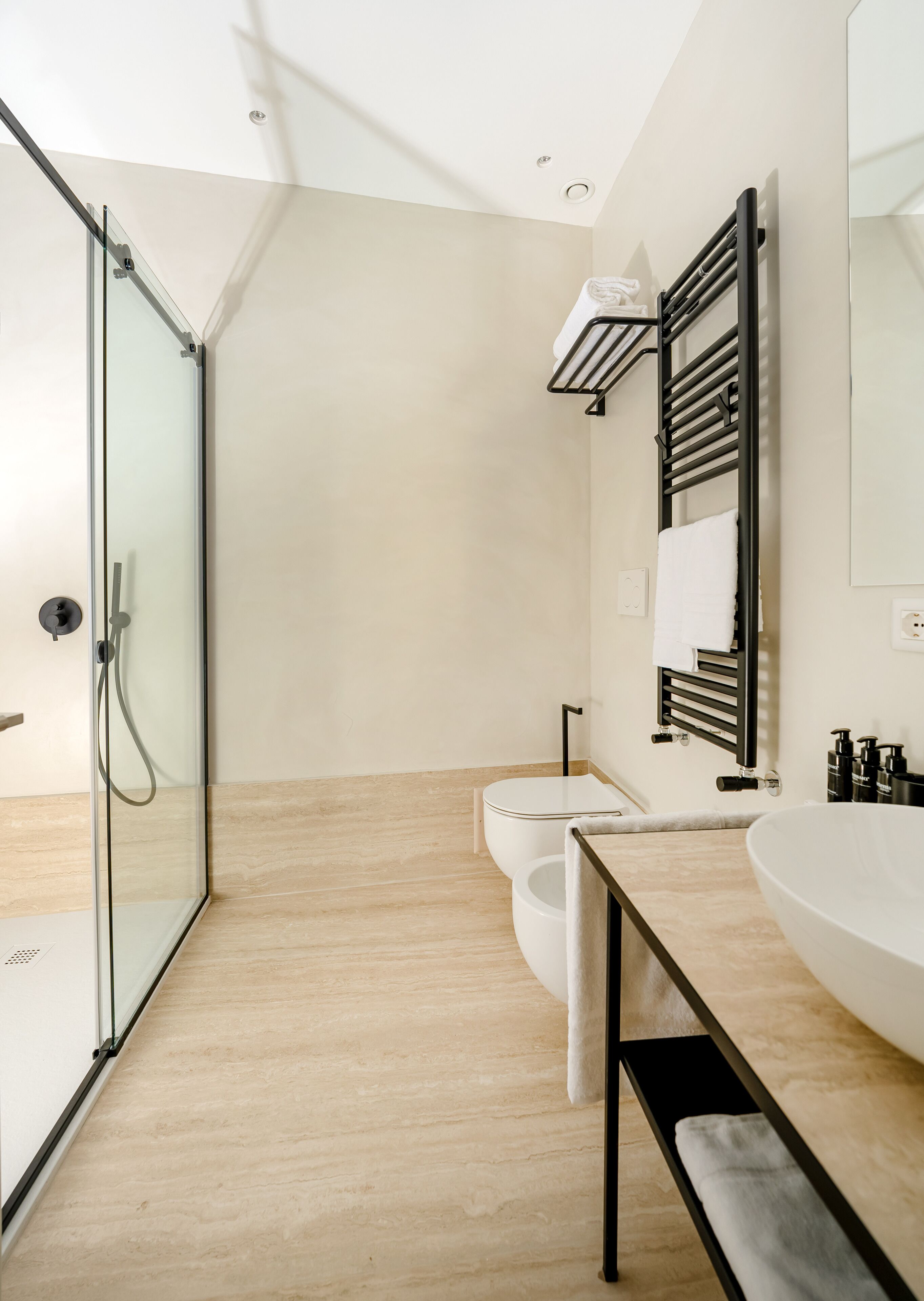 Un bagno moderno con cabina doccia in vetro, un water, un lavabo con porta asciugamani e uno specchio.