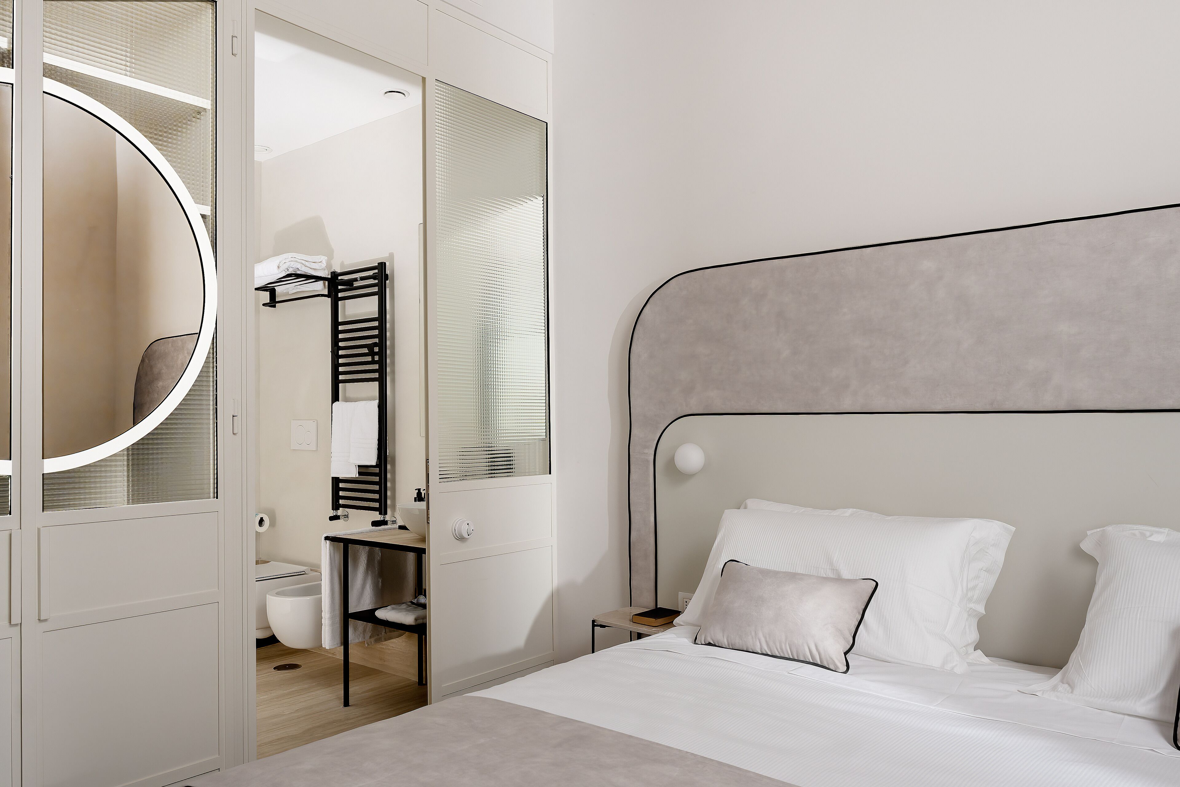Une chambre à coucher moderne avec un lit, une table de chevet, un miroir et une armoire.