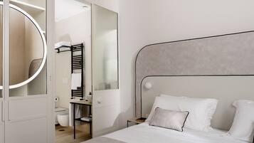 Une chambre à coucher moderne avec un lit, une table de chevet, un miroir et une armoire.
