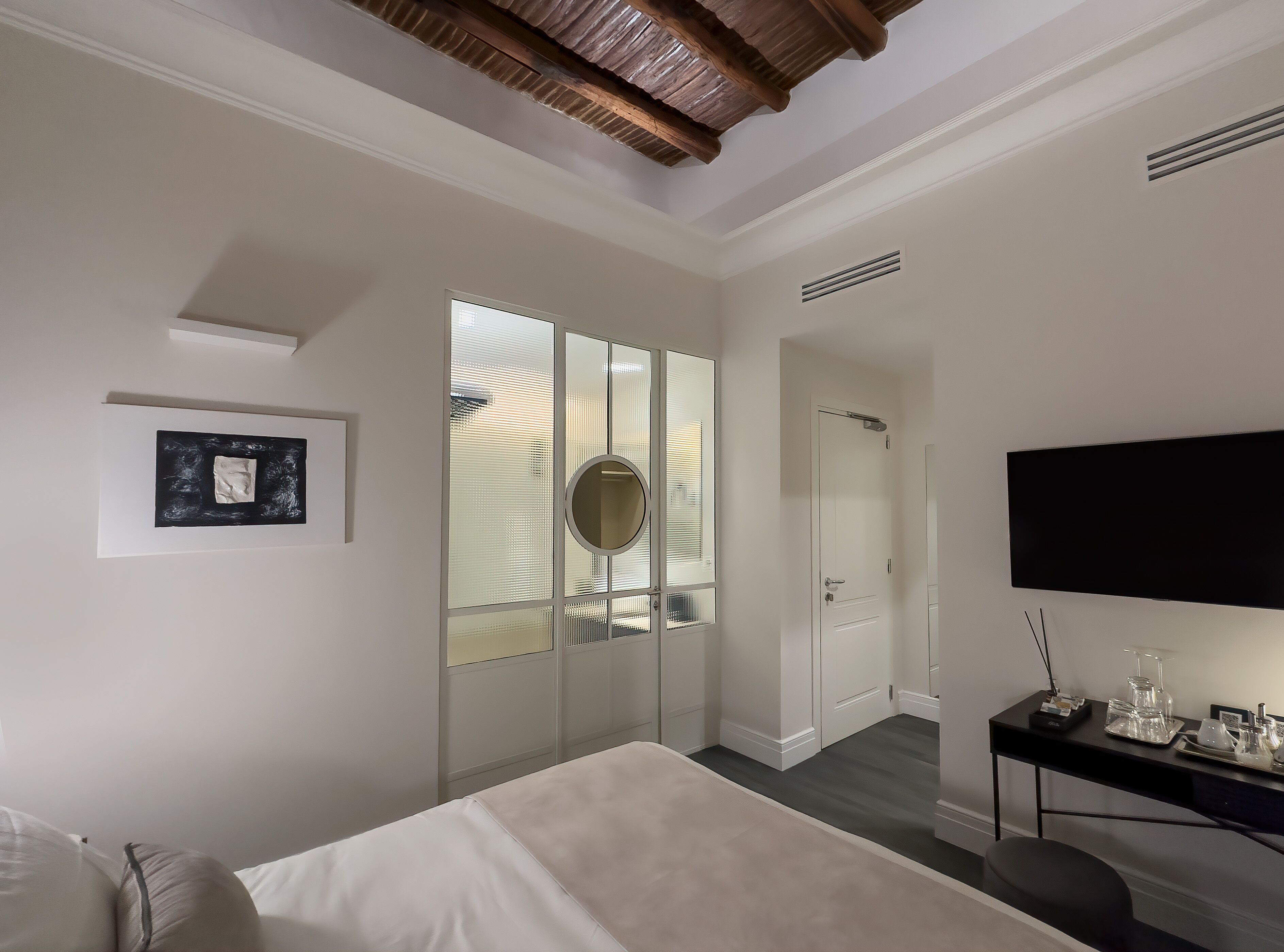 Un dormitorio moderno con una cama grande, un escritorio con televisor de pantalla plana y un vestidor.