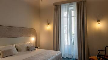 Una camera da letto con un letto grande, soffitto in legno e vista all'aperto attraverso una finestra con tende.