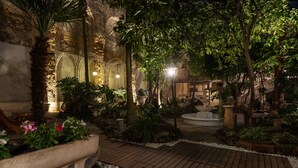 Un jardín al aire libre con muros de piedra, plantas en macetas y un sendero de madera.