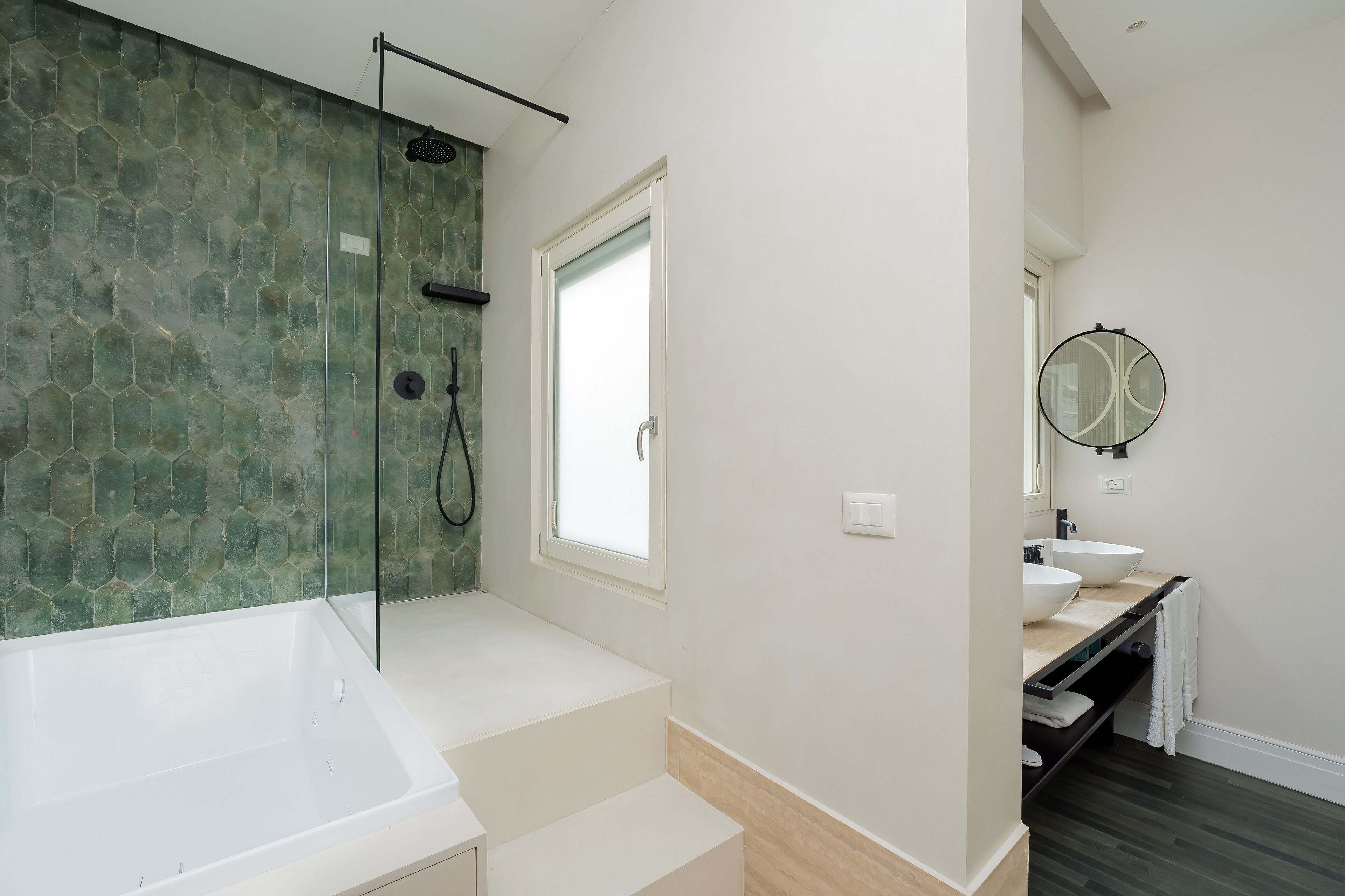 A modern bathroom with a large bathtub, a shower area with a glass door, and a vanity with a mirror.