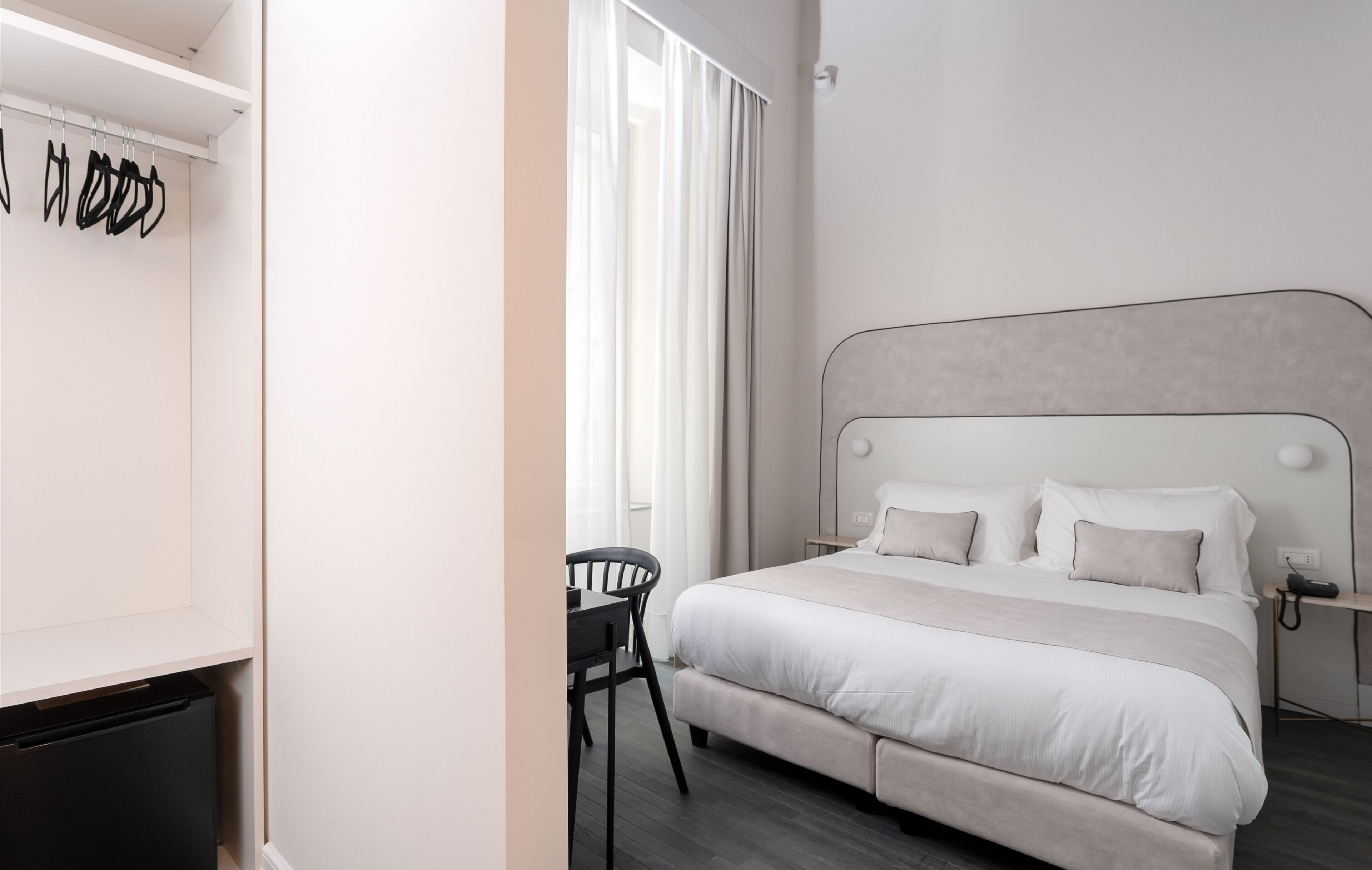 Ein modernes Schlafzimmer mit einem großen Bett, einem Nachttisch und einem Sessel.