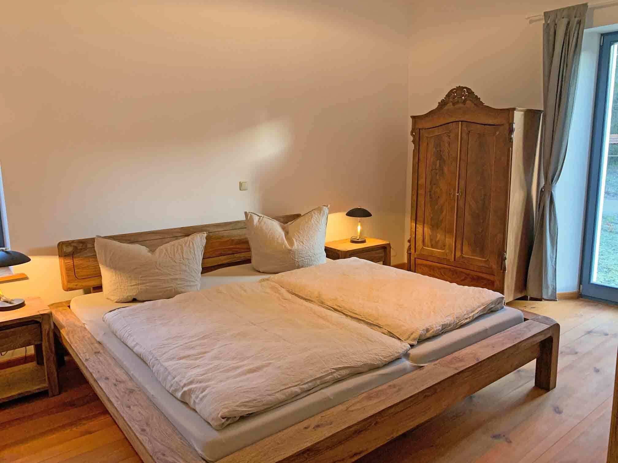 Een slaapkamer met een houten bed, twee nachtkastjes, een kaptafel en een kledingkast.