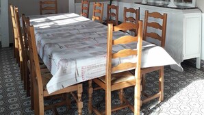Ein Esszimmer mit einem langen Tisch, Holzsesseln, einem weißen Schrank und einem gemusterten Boden.