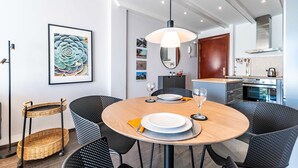 A modern dining area with a round table, black chairs, and a hanging light fixture. - Apartment in the Heart of Fuengirola (Fuengirola)