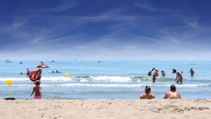A beach with people swimming and playing, boats in the water, and a clear sky. - Apartment in the Heart of Fuengirola (Fuengirola)