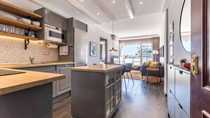 A modern kitchen with a central island, built-in appliances, and a dining area with a sofa and table. - Apartment in the Heart of Fuengirola (Fuengirola)