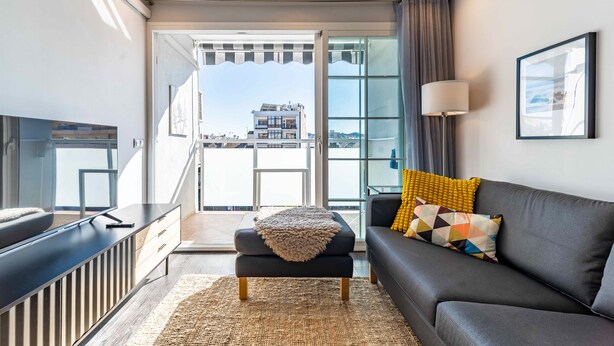 A modern living room with a sofa, ottoman, and a flat-screen TV. - Apartment in the Heart of Fuengirola (Fuengirola)