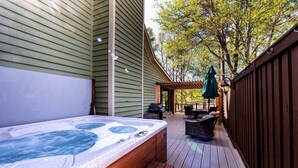 Ein Whirlpool auf einer Holzdielen-Terrasse mit Gartenmöbeln und einer Pergola.