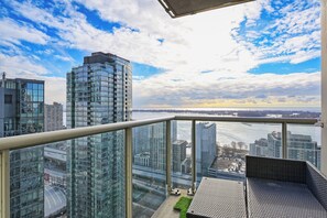 Experience panoramic city views from this urban retreat, featuring a balcony with a seating area and lush greenery.