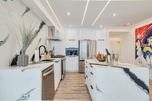 Enjoy cooking in this well-equipped kitchen with a central island, sink, and stainless steel refrigerator.