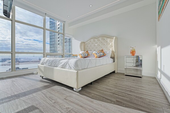 Relax in this serene bedroom with a large bed, city views, and a peaceful atmosphere.