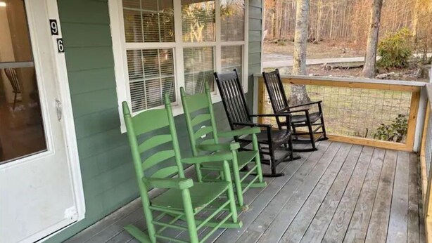 A porch with green rocking chairs and a wooden deck. - Maggie's Place (Lookout Mountain)
