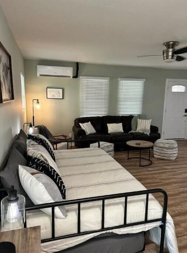 A bedroom with a bed, a sofa, a coffee table, and a ceiling fan.