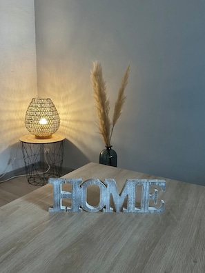 A wooden table with a 'HOME' sign, a lamp, and pampas grass in a vase.