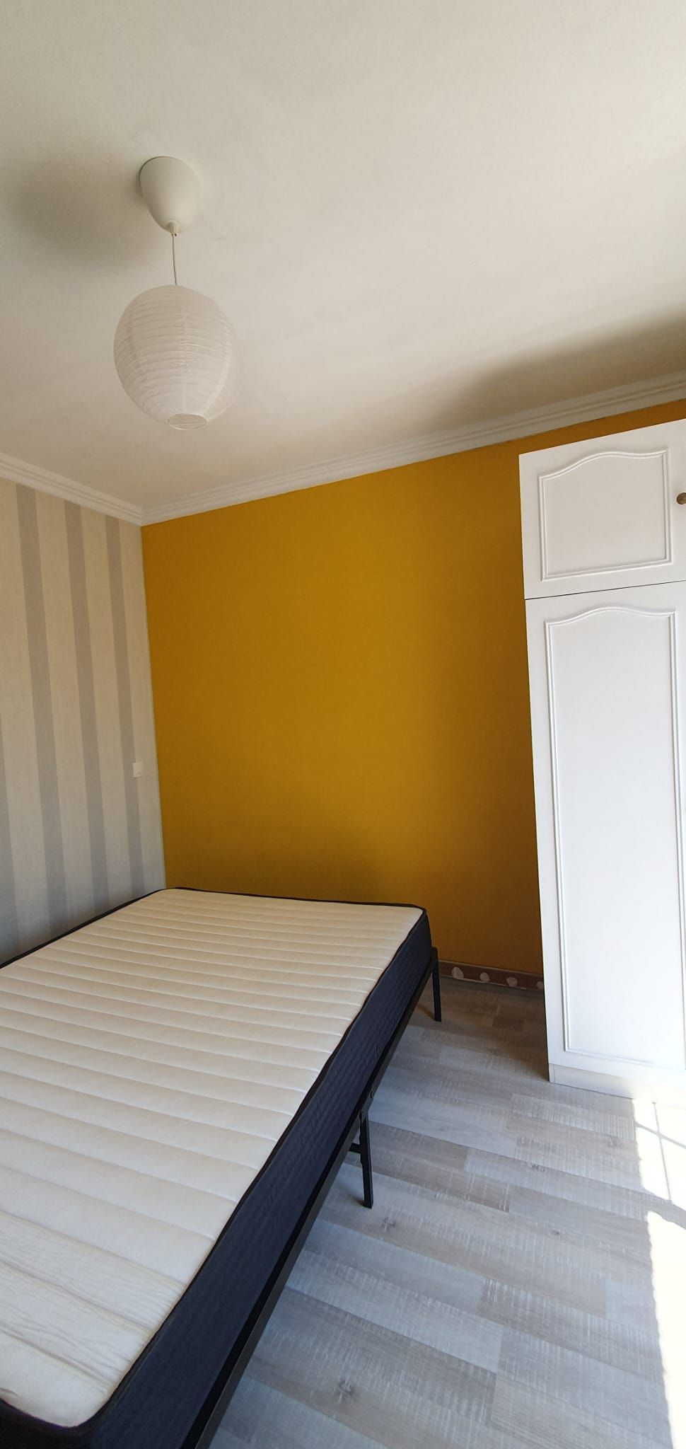 Una stanza con un letto, un armadio e una lampada a soffitto.
