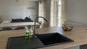 A modern kitchen with a sink, countertop, and a dining area with a table and chairs. - Appartement Nature by Reine DU SUD au Coeur de Narbonne (Narbonne)