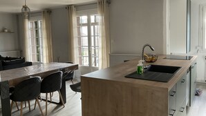 A modern kitchen with a wooden island, black chairs, and a built-in sink. - Appartement Nature by Reine DU SUD au Coeur de Narbonne (Narbonne)