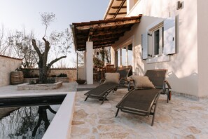 A stone pool with lounge chairs, a pergola, and a dining area with outdoor furniture. - Authentic stone villa Beatrice with private pool, near Pula. (Galižana)