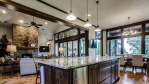 Un'ampia cucina con una grande isola, pavimento in legno e parete decorativa in pietra.