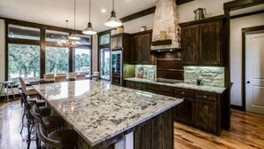 Un'ampia cucina con un'isola grande, mobili in legno scuro e una parete decorata con pietra.