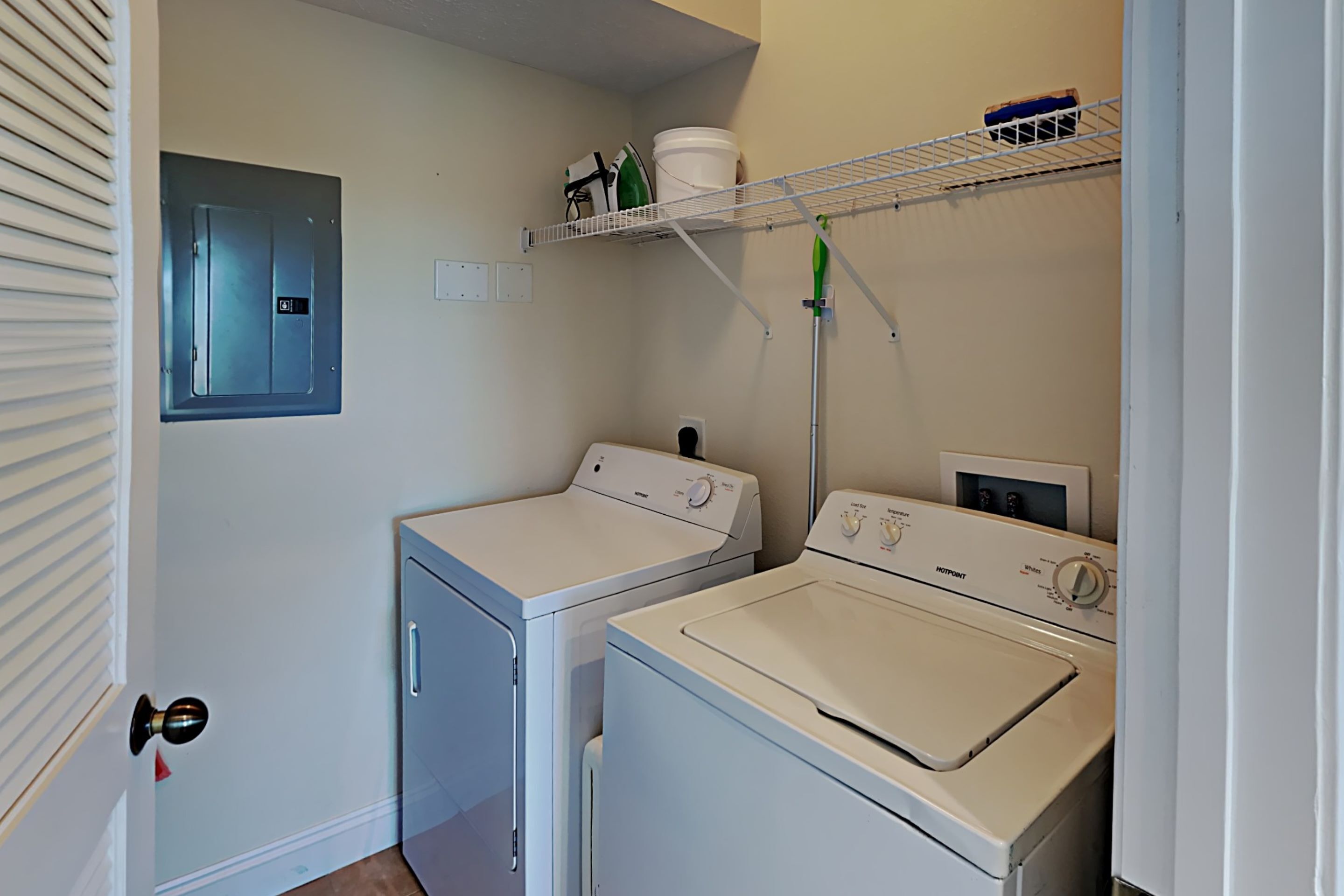 Un cuarto de lavado con dos lavadoras, un tendedero y un armario de servicios.