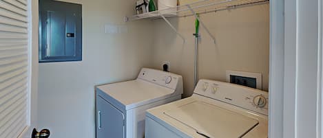 A laundry room with two washing machines, a drying rack, and a utility cabinet.