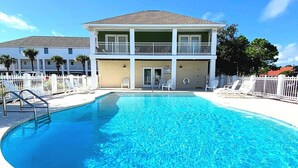 A pool area with a two-story building, white railings, and lounge chairs. - Bonita Point Condo II #214E by Resort Collection (Panama City Beach)