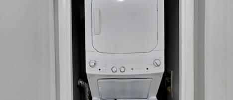 A front view of a white washing machine in a laundry room with a black wall and a white door.