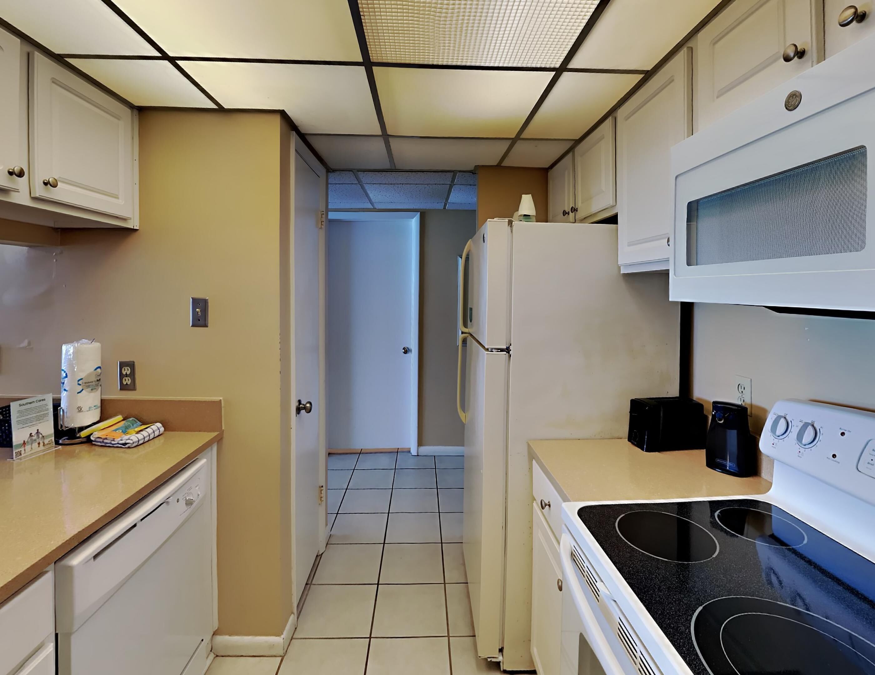 A compact kitchen with white cabinets, a microwave, a stove, and a refrigerator.