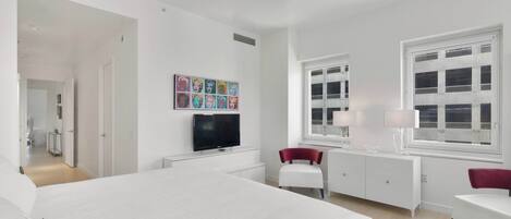 Habitación de hotel moderna con una cama grande, televisión, escritorio y ventana con vistas.