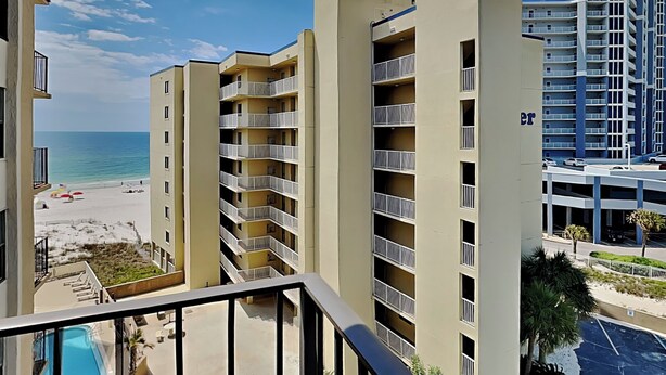 Un hôtel à plusieurs étages doté de balcons, d’une piscine et offrant une vue sur la plage.