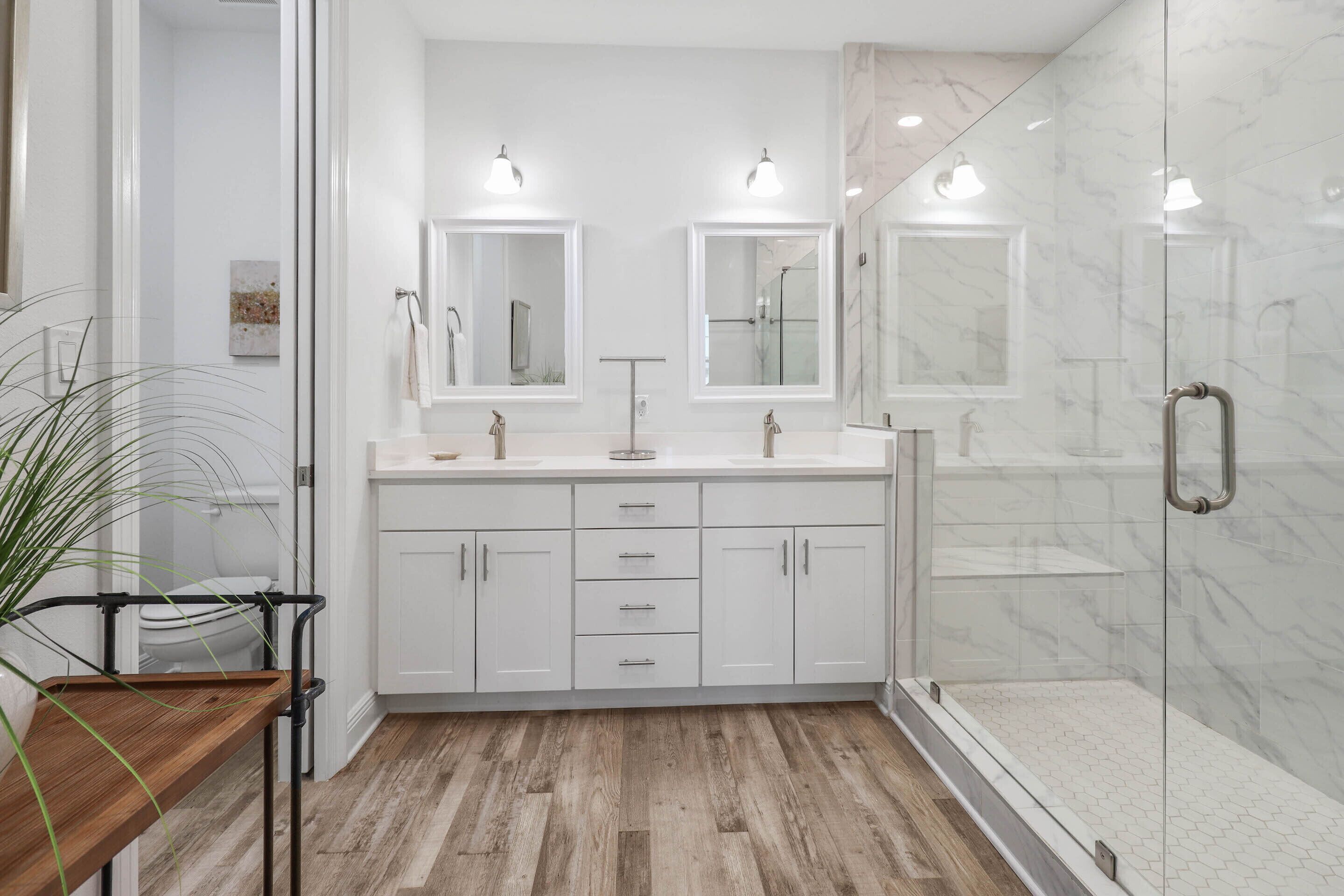 Un baño moderno con dos lavamanos, una ducha y cabina de ducha con paredes de vidrio.
